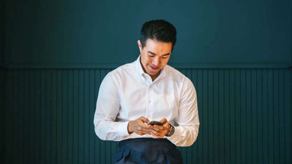 A man in white shirt looking at his phone.